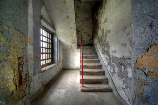A staircase surrounded by rusty and dirty walls in an abandoned building