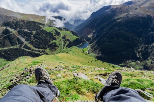 Beautiful view of a valley with green grass and forests from a person sitting above the clouds on a sunny day