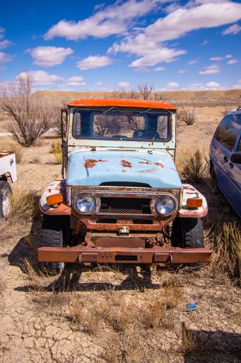 The front of the rusty truck against a beautiful sky