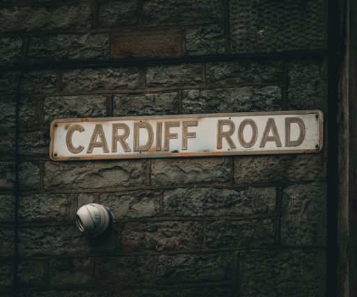 A Cardiff Road street sign mounted on a brick wall.