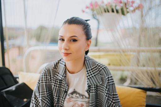 A shallow focus shot of a beautiful Caucasian girl wearing a checkered shirt, sitting outdoors