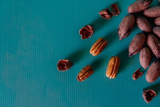A closeup shot of whole and shelled pecans on a green surface