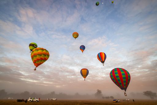 A scenic view of hot air balloons floating across a foggy landscape in Western Australia