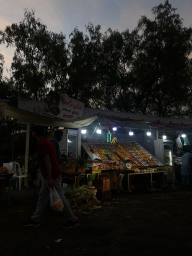 A group of people shopping in a bustling marketplace during the evening hours