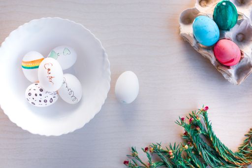 A top view of colorful easter eggs with fir branches on a wooden table