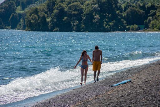 a young couple walking along a lake beach