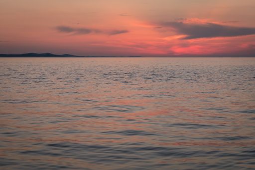 The beautiful view of the calm ocean under the colorful sky during sunset in Dalmatia, Croatia