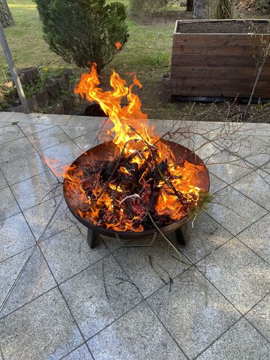 A vertical shot of flaming bonfire on a pot in the backyard