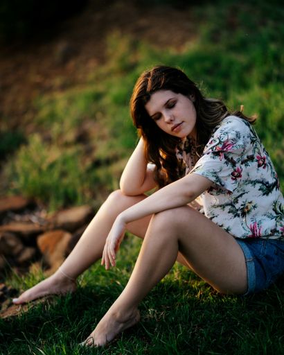 A beautiful young woman from South Africa in casual clothes resting on the grass