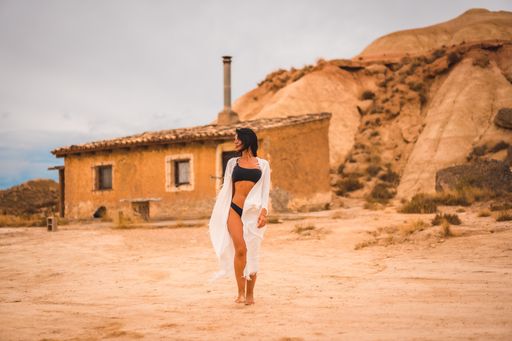 A young brunette Caucasian girl in a white dress and a black bikini posing in the desert of Las Bardenas, Navarra. Spain