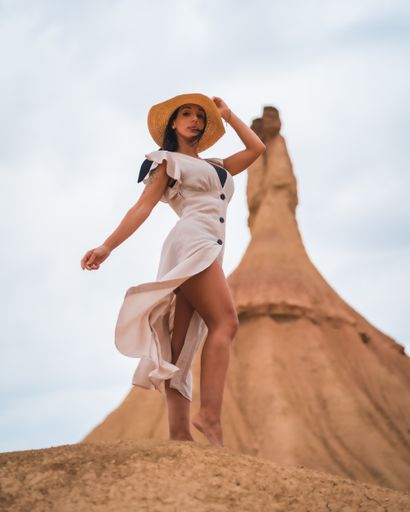A young brunette Caucasian girl with a white dress and a straw hat in the Castildetierra of the Bardenas Reales desert, Navarra. Spain