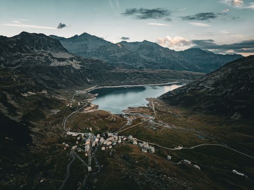 An aerial view of a tranquil lake surrounded by mountains on a cloudy day in Montespluga, Italy