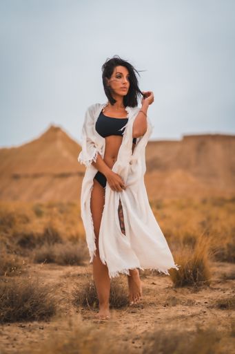 A brunette Caucasian model girl in a white dress and a black bikini in the desert of the Bardenas Reales, Navarra. Spain
