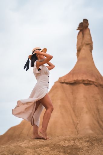 A brunette Caucasian model with a white dress and a straw hat in the Castildetierra of the Bardenas Reales desert, Navarra. Spain