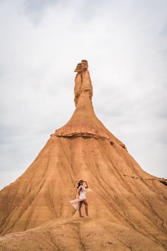 A runette Caucasian girl with a white dress and a straw hat in the Castildetierra of the Bardenas Reales desert, Navarra.