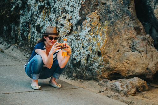 A woman squats on the ground while taking pictures on the phone