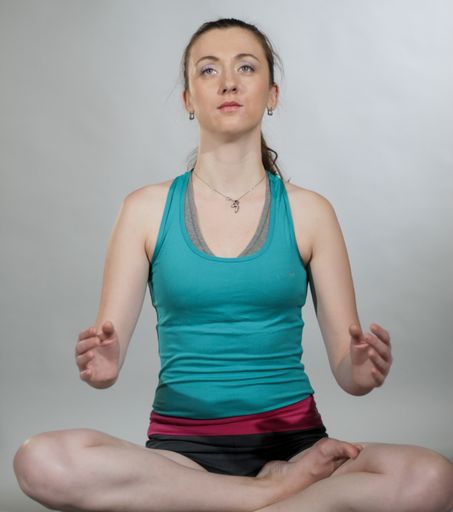 A young woman in a lotus pose is practicing yoga