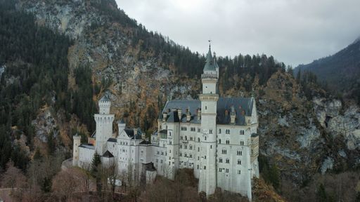 An aerial view of the historic Neuschwanstein Castle on top of a lush mountain
