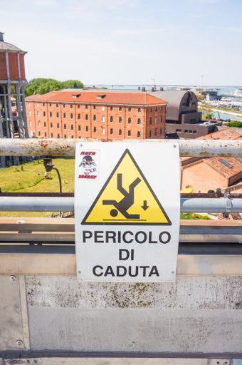 Sign warning for risk of falling on a metal barrier of a high parking garage