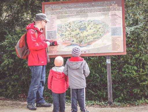 Father with two children looking at a information map at the arboretum park