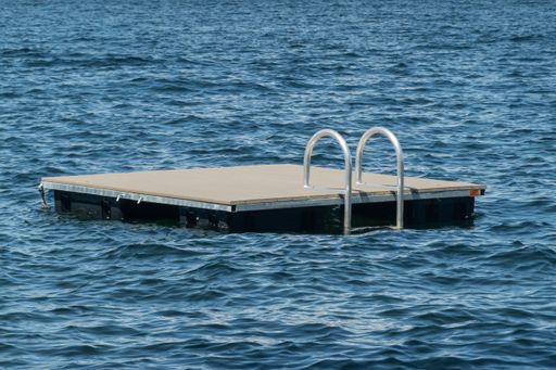 A small wooden dock floats on the calm waters of New Hampshire's Lake Winnipesaukee