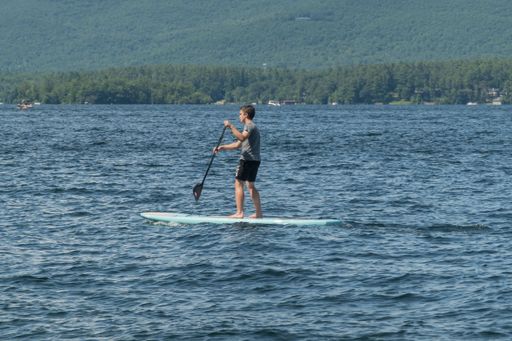 A young man enjoying a sunny day out on the water, navigating his way through the waves on a surfboard