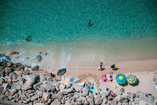 An aerial view of a beach with tourists, colorful umbrellas in the Caribbean sea