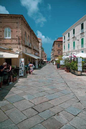 A vertical shot of an  urban street with buildings in the background and multiple people, Italy