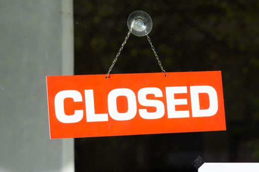 A closeup shot of a red closed sign on a glass door of a shop