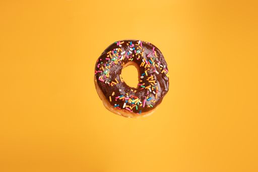 A glazed donut isolated in a yellow background