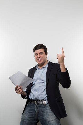 A vertical shot of a happy businessman cheering while holding a paper