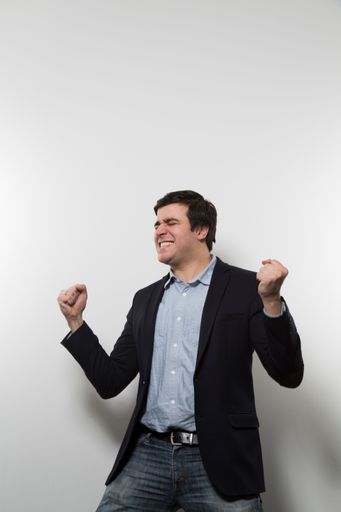 A vertical shot of a happy male sheering while wearing a suit