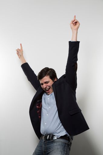 A vertical shot of a happy male cheering with his hands pointing up