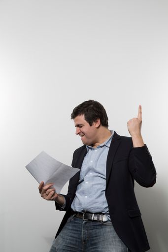A vertical shot of a happy male cheering while holding a paper