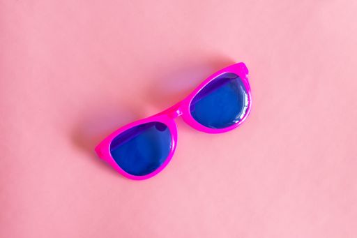 A top view shot of a sun glasses on the pink background