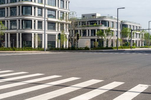 An empty asphalt road in a modern city with office buildings in the background