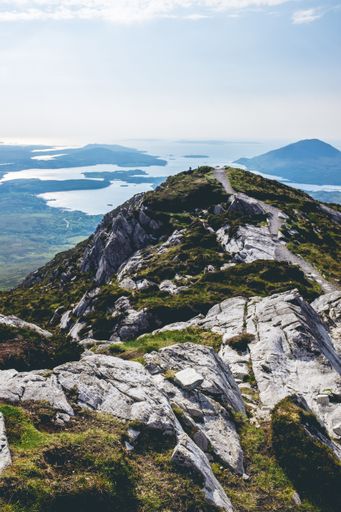 An aerial view of a rocky mountain peak covered with greenery on a sunny day