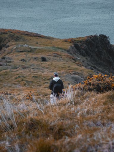 A vertical shot of a male backpacker hiking on a cliff
