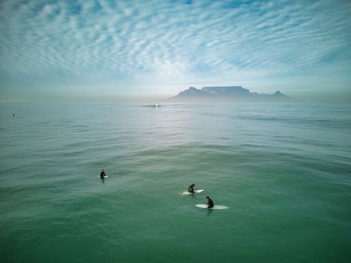 The surfers enjoying the beautiful day in the ocean on their surfboards with Table mountain in the background