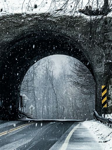 A vertical shot of a road through a small tunnel on a snowy day