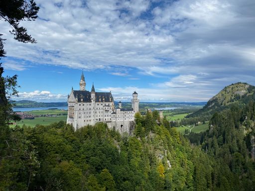 This stunning aerial shot shows a majestic castle perched atop a mountain, overlooking the vast valley below
