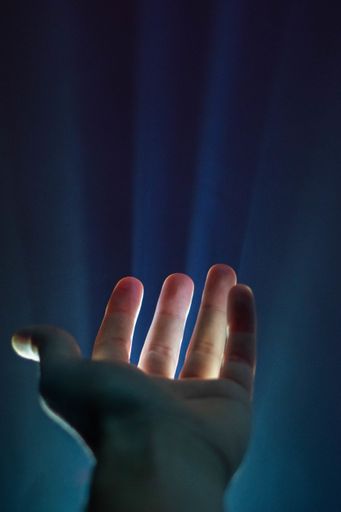 A vertical shot of a person's hand with a light shining through the fingers - great for a background