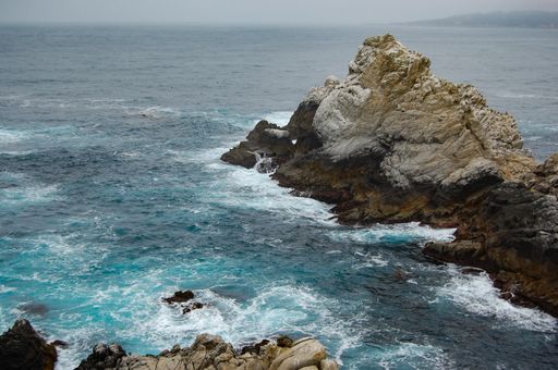 A beautiful shot of rocks in the sea under a foggy sky