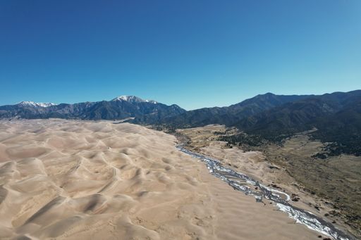 A scenic landscape of the Great Sand Dunes in Colorado, with vast, sweeping sand dunes