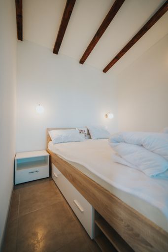 A vertical shot of a minimalistic room interior with a queen-size bed