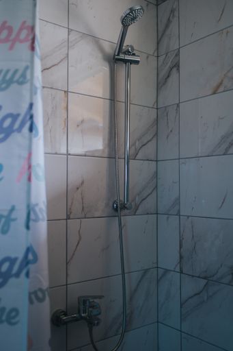 A vertical shot of a bathroom interior with a shower and marble tiles