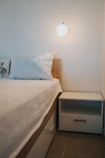 A vertical shot of a made-up bed and a bedside table