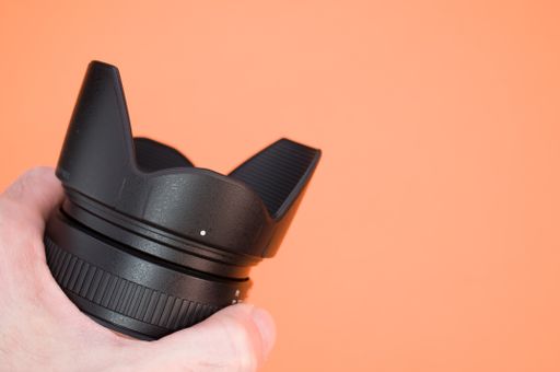A closeup shot of a hand holding a black camera on a colorful background