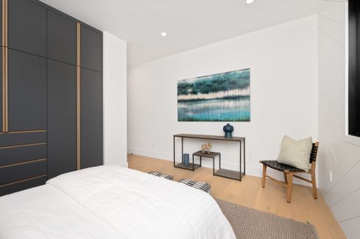 A modern bedroom featuring black cabinets, wooden flooring and a wall-mounted painting