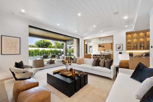 An inviting and stylish modern living room interior featuring white furniture, walls and large windows that bring in lots of natural light